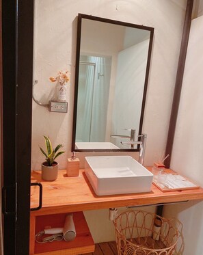 A bathroom with a white sink, a mirror, a potted plant, a small wooden box, and a wicker basket. - 開放式廚房，寬敞自由舒適大空間，鄰近孔廟商圈 (Tainan City)