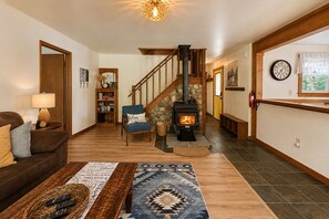 Una sala de estar acogedora con chimenea, una escalera, una estantería y una zona de estar cómoda.