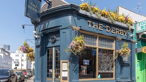 A blue building with a sign reading "THE DERBY BBQ DEPT."