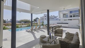 En modern uteplats med pool, solstolar och en matplats.