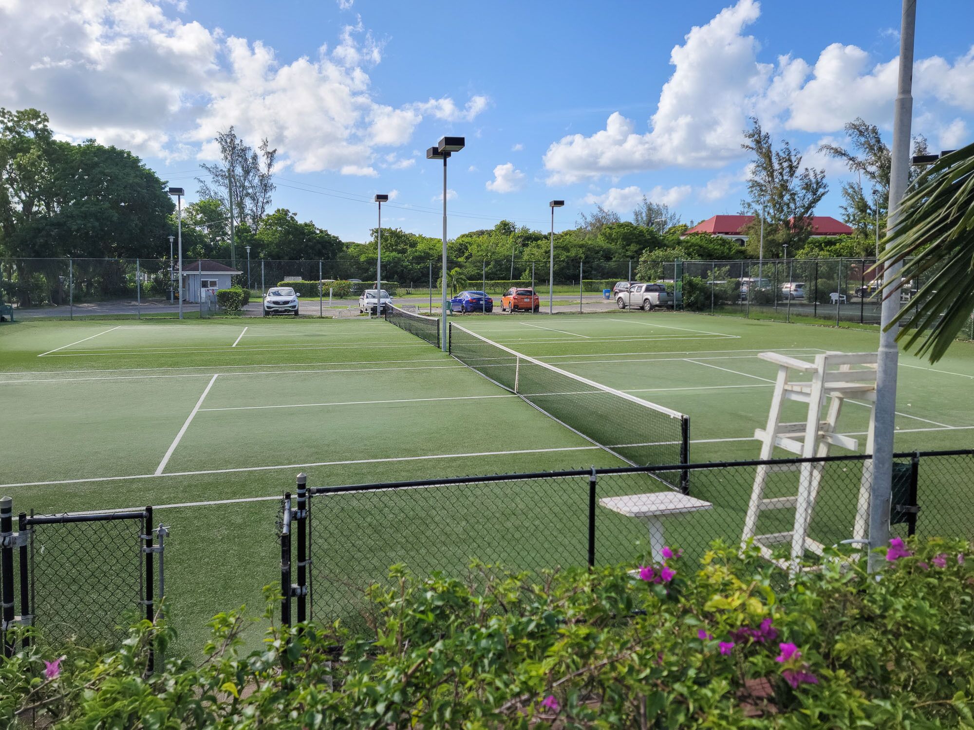 A tennis court with a fence, a table, and a chair.