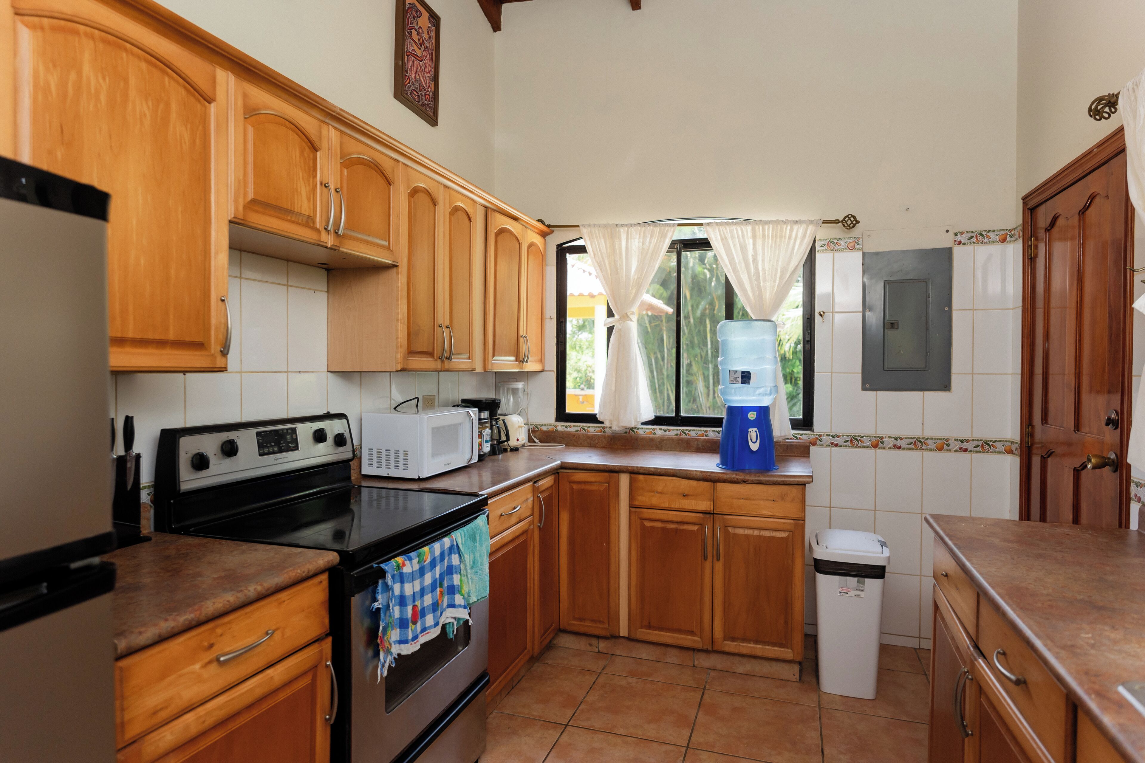 A kitchen with wooden cabinets, a stove, a microwave, and a water dispenser.