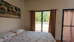 Een slaapkamer met een bed, een schilderij aan de muur en uitzicht door het raam.