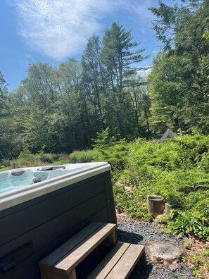 A hot tub in a forested area with a wooden bench and a stone stump nearby. - StarryPinesCottage w Cedar Sauna Steps to Trails (Catskill)