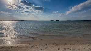 A beach with clear skies and sunlight reflecting on the water.