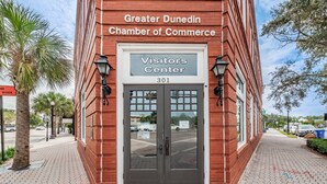 A red brick building with a sign reading "Greater Dunedin Chamber of Commerce Visitors Center 301".