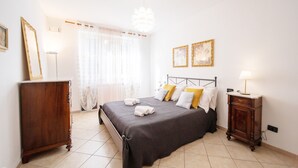 Quarto bem arrumado com cama, mesas de cabeceira e guarda-roupa.