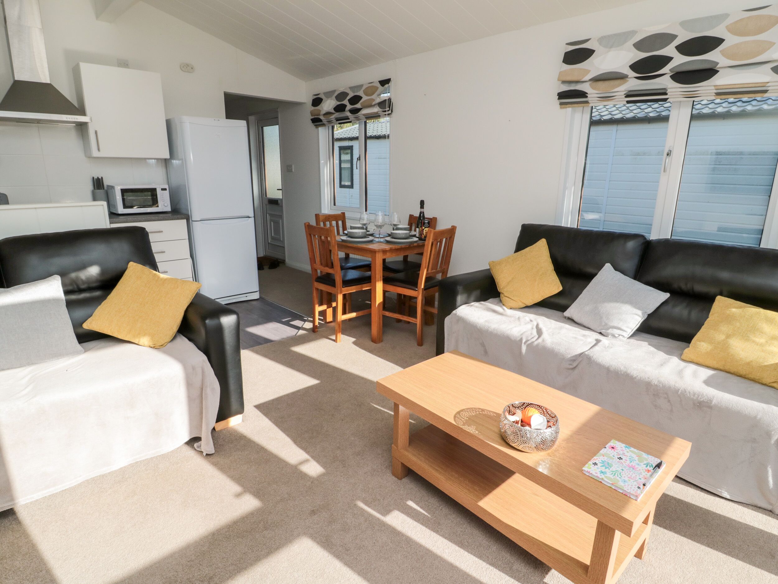 A modern living room with a sofa set, a coffee table, and a dining area with a table and chairs.