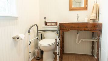 A bathroom with a toilet, a sink with a wooden countertop, a mirror above the sink, and a towel hanging on the wall.