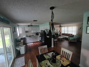 A spacious living area with a dining table, kitchen, and seating area. - Mermaid retreat in the country (Grant-Valkaria)