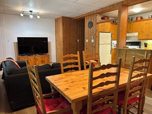 Olohuone, jossa on televisio, sohva, puinen ruokapöytä ja tuolit.