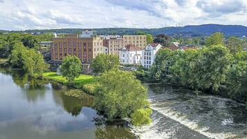 Ein Blick auf den Fluss mit einem historischen Gebäudeensemble, bestehend aus mehreren Gebäuden, darunter ein markantes Gebäude mit roten Backsteinen und mehreren weißen Fassaden.