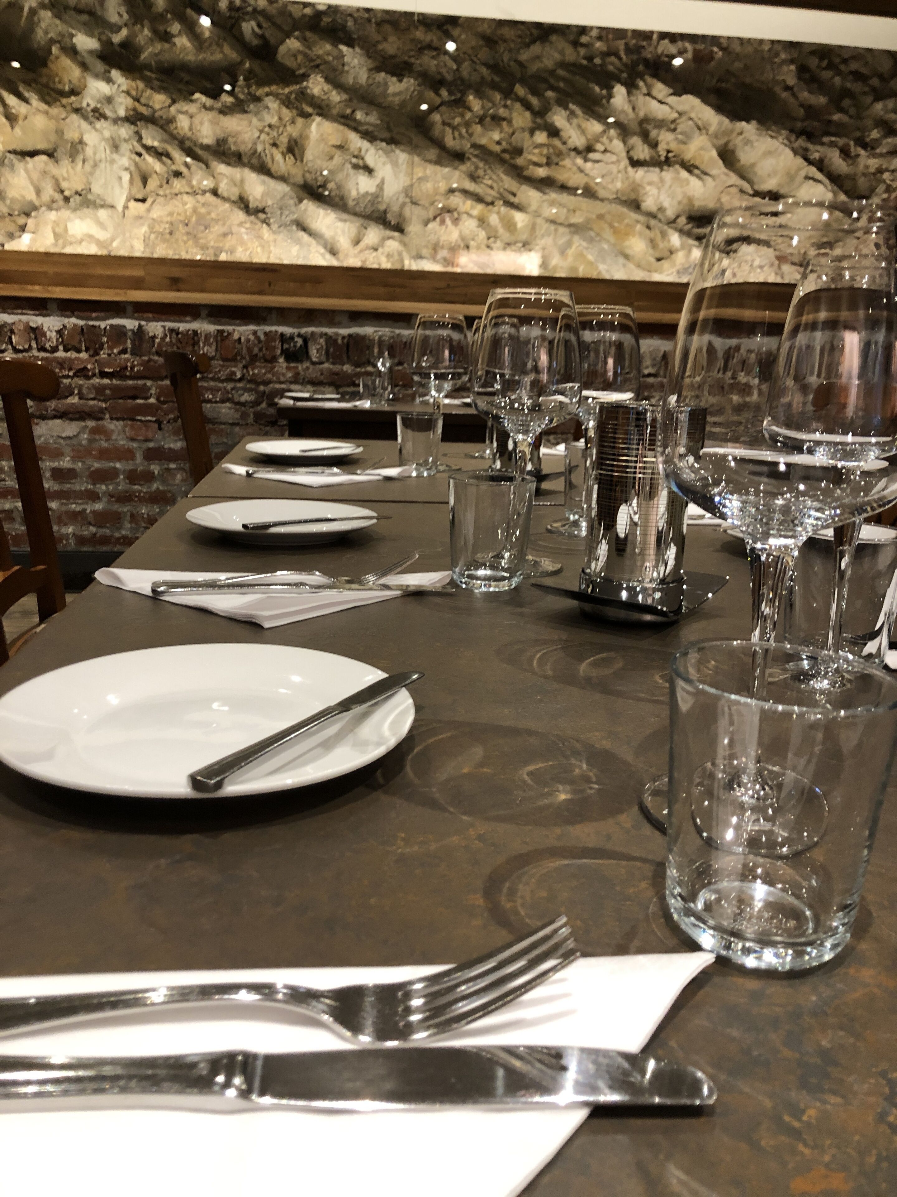 A dining table set for a meal with plates, cutlery, and glasses.