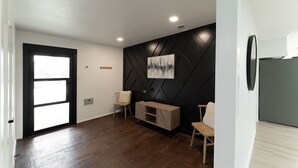 A modern interior with a black geometric wall panel, a wooden cabinet, and a door with a frosted glass panel. - One of a kind home in the city (Arlington)