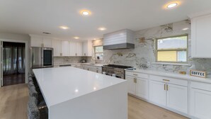 A modern kitchen with white cabinetry, a large island, and a built-in stove. - One of a kind home in the city (Arlington)
