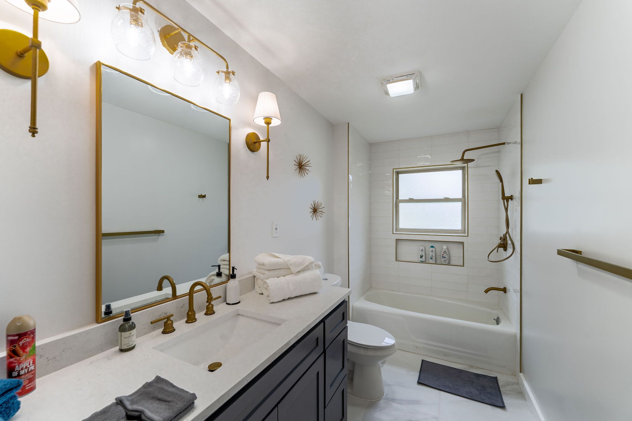 A modern bathroom with a large mirror, dual sinks, a toilet, and a bathtub.