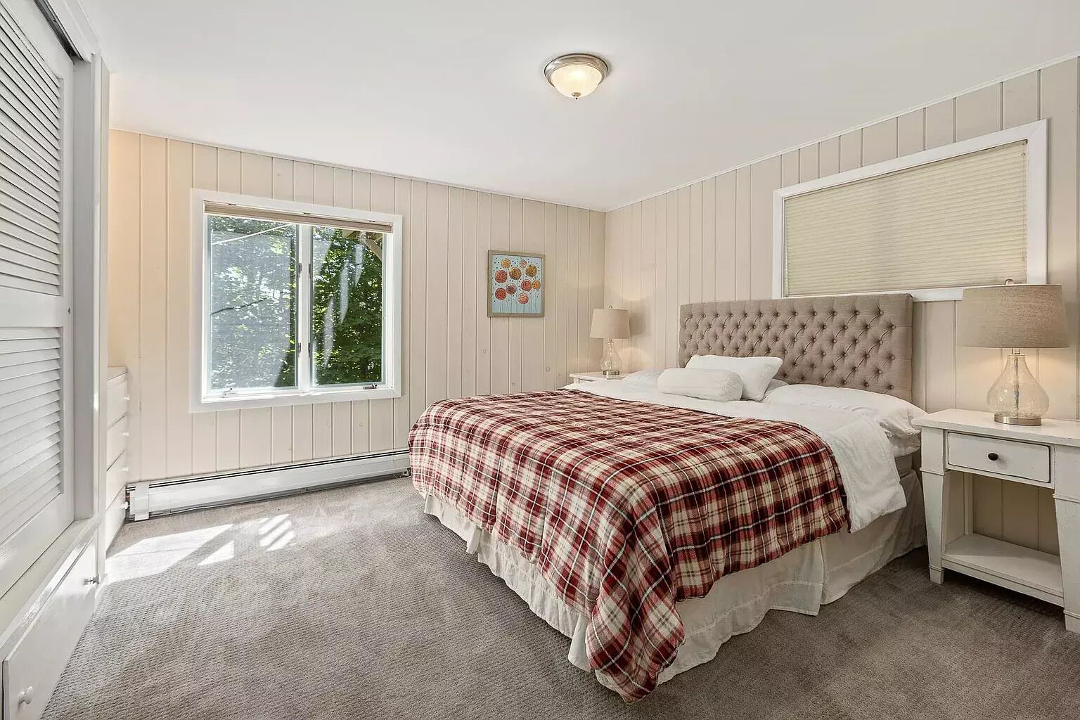 Quarto com cama, duas mesas de cabeceira, uma janela e um radiador.