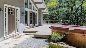 Una casa con terraza, jacuzzi y un camino de piedra que lleva a la entrada.
