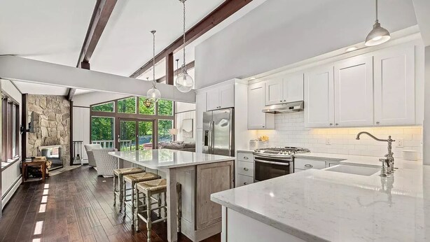 Una cocina moderna con armarios blancos, una isla grande y una chimenea de piedra.