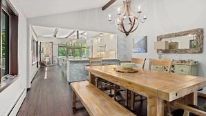 Una cocina amplia con una isla grande, mesa de comedor de madera y asientos tipo banco.