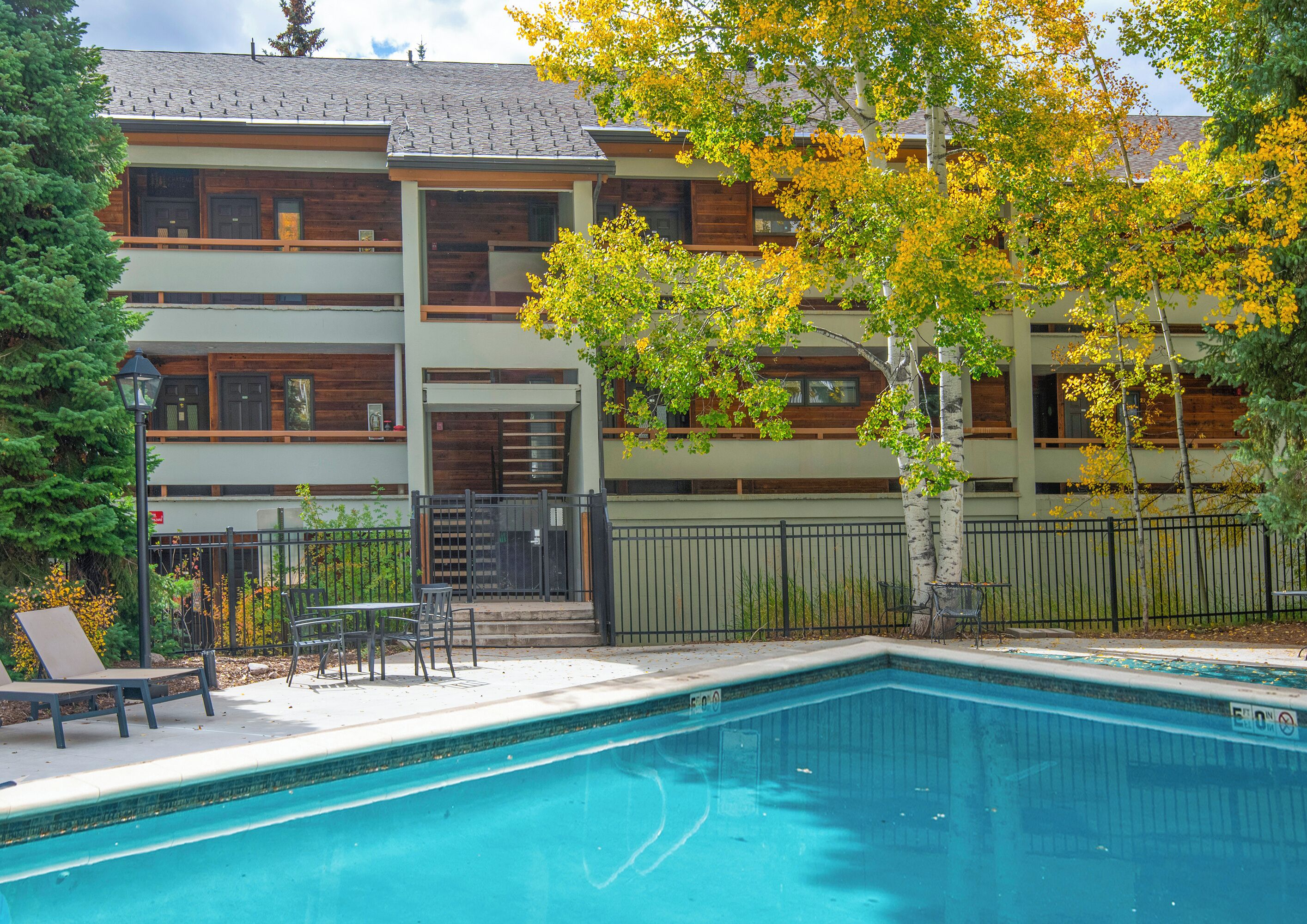 En moderne bygning med flere etager og en swimmingpool foran.