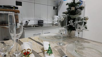 Una mesa de comedor lista para una comida, con vasos transparentes, un pequeño árbol de Navidad y una servilleta decorativa.