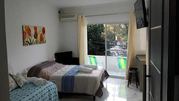 Un dormitorio con dos camas, un televisor y un balcón con sillas.