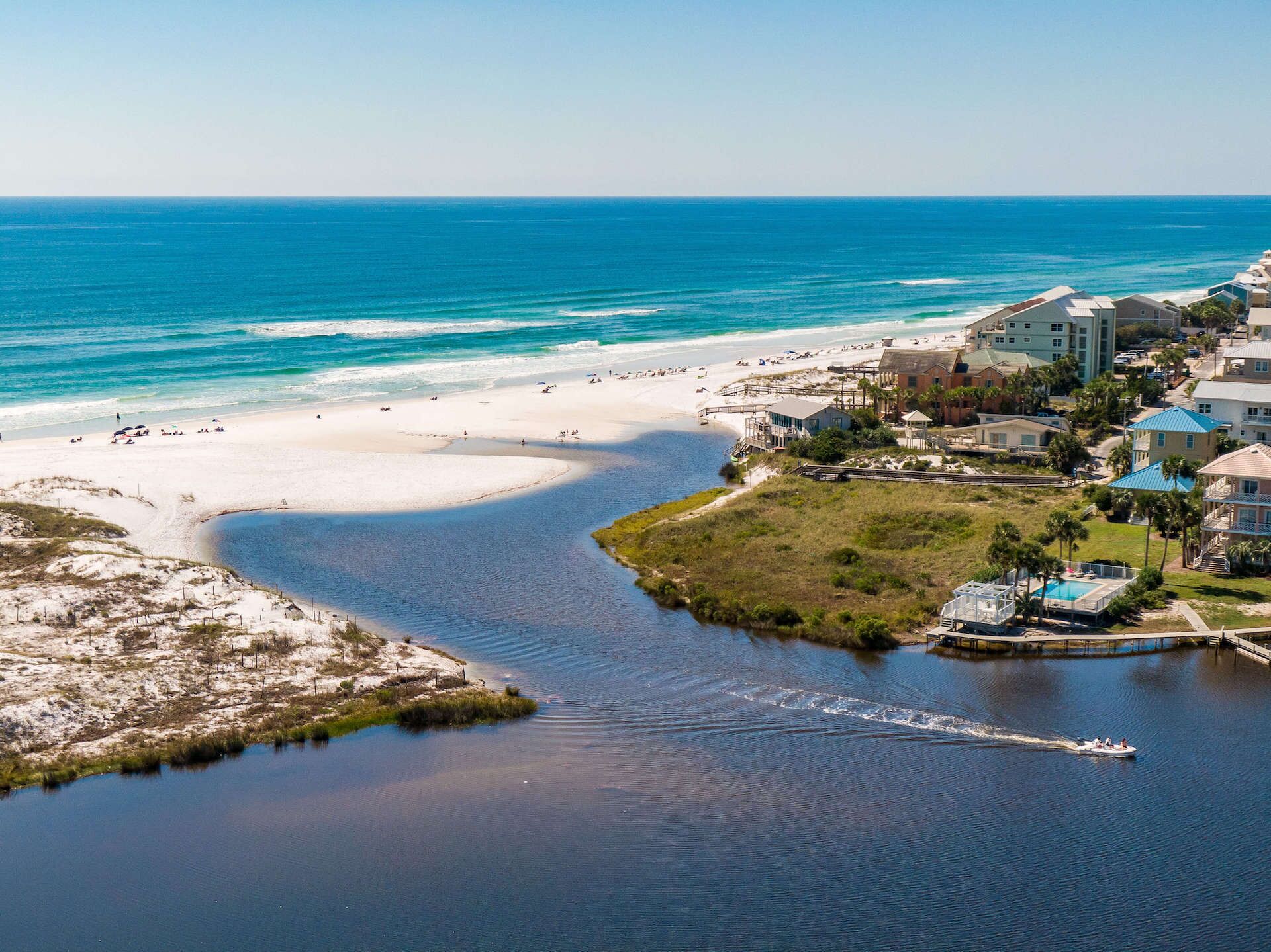 A coastal area with a beach, a marina, and residential buildings.