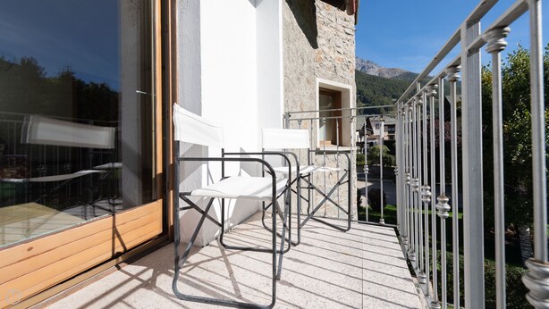 A balcony with outdoor seating, a stone building, and a view of mountains. - Milano 35 - Three Bedroom Apartment, Sleeps 6 (Bormio)