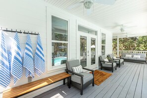 A covered porch with a seating area, a pool visible through the windows, and a wooden bench. - Private Heated Pool • 5 Min Walk to Beach • Peaceful Backyard (Inlet Beach)