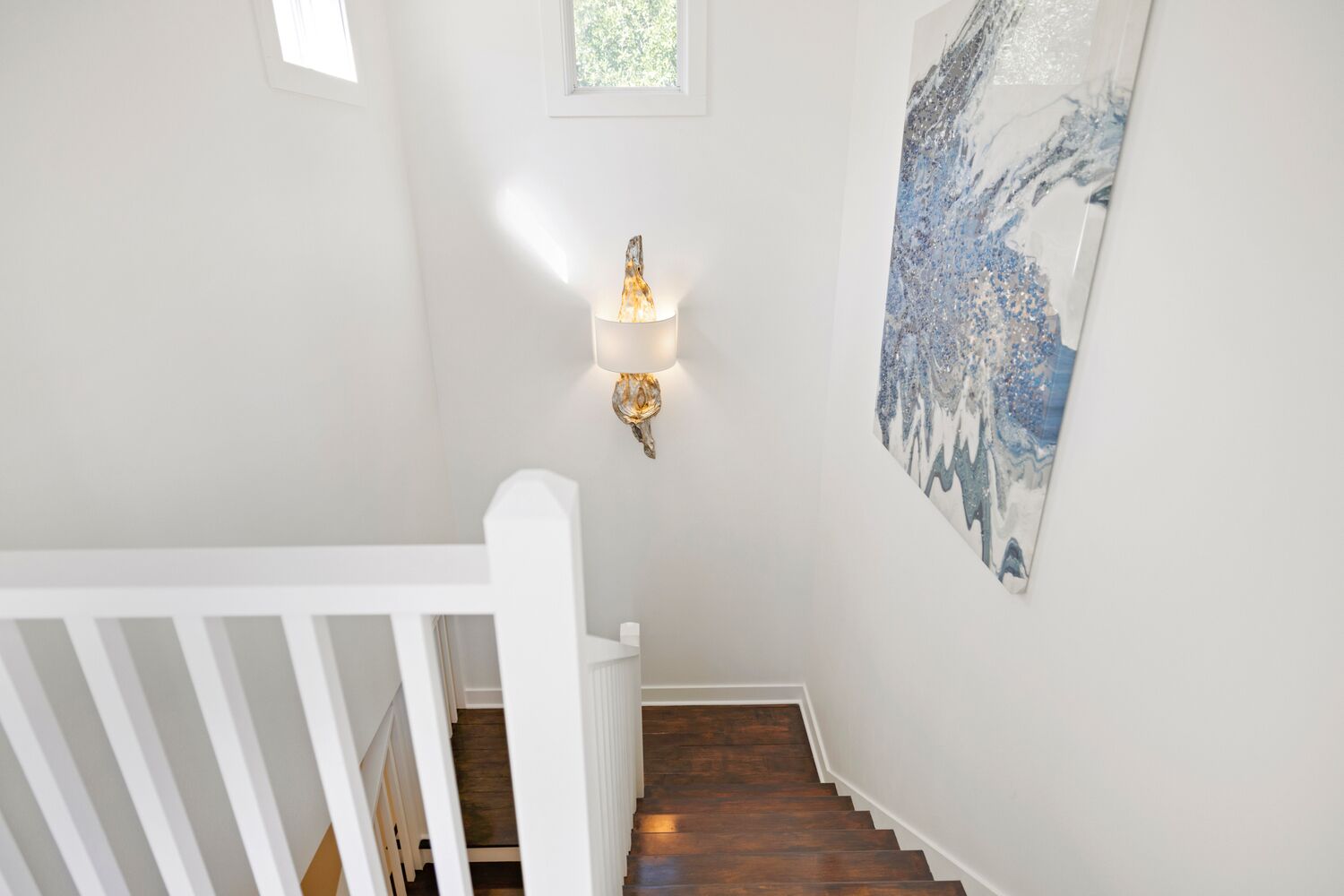 A staircase with white railings and a wall-mounted light fixture.