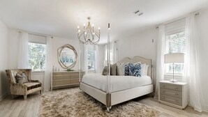 Une chambre à coucher avec un grand lit, une chaise, une commode, un miroir et une lampe.