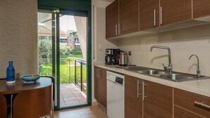 A modern kitchen with wooden cabinets, a dishwasher, a coffee maker, and a sink. There is a dining table with chairs and a bowl on it. - Apartment in Pals with community pool (Pals)