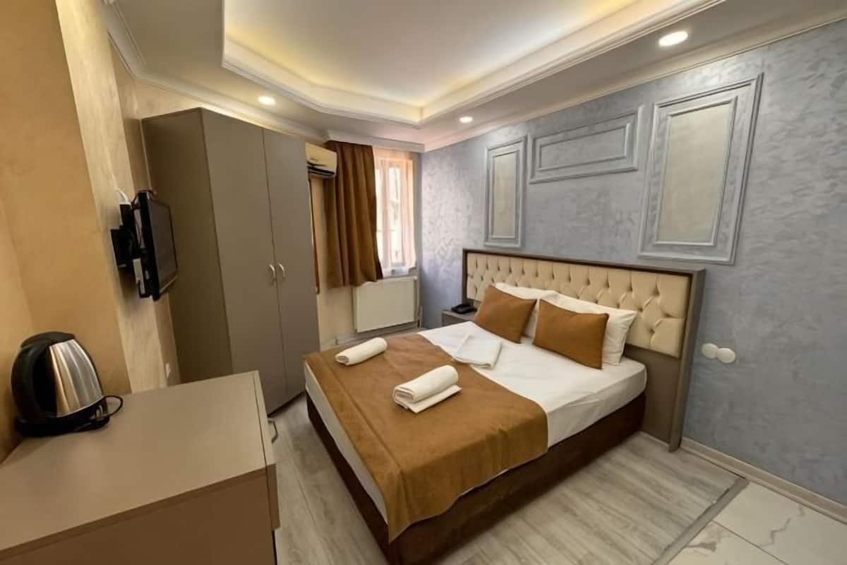 Une chambre d’hôtel équipée d’un lit, d’un bureau, d’une télévision et d’une armoire.