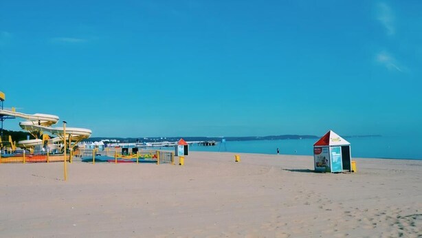 A beach with a lifeguard tower, a small hut, and a water slide structure. - Guesthouse Baltic (Gdansk)