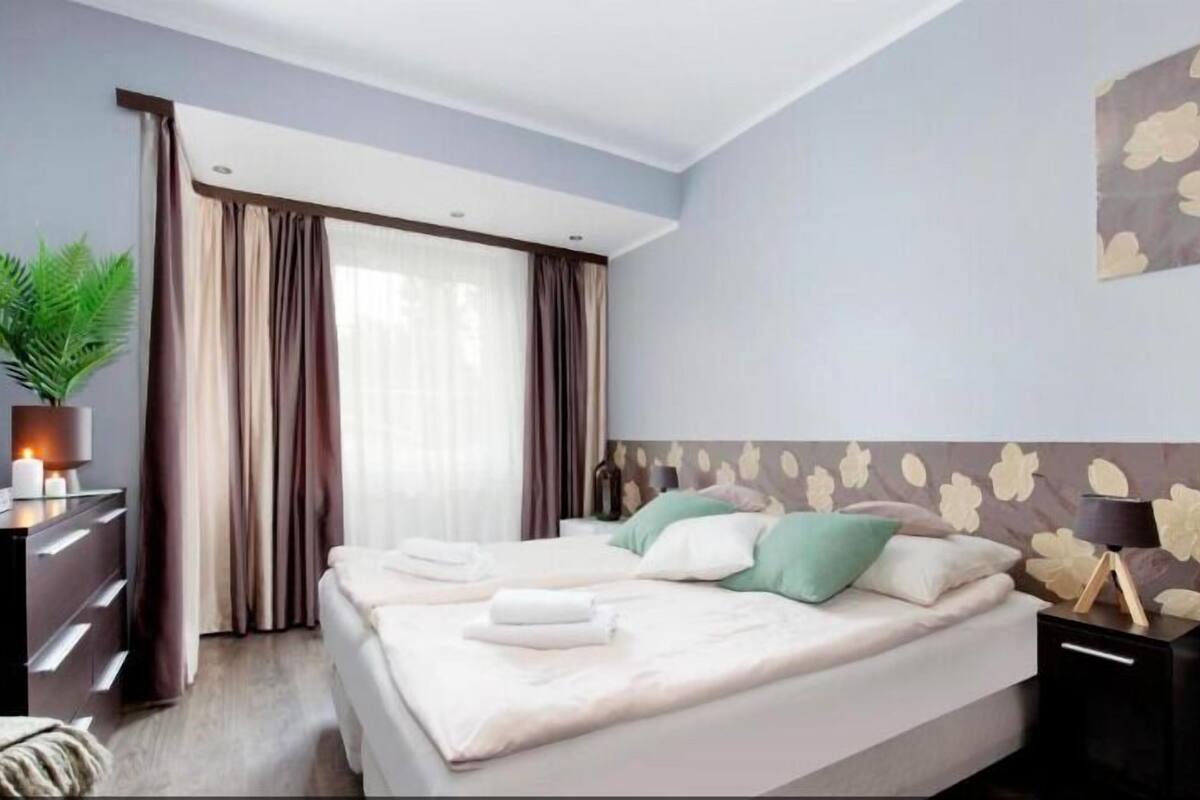Una habitación de hotel moderna con una cama grande, un escritorio con lámpara y una planta en maceta.
