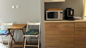 A compact kitchen with a microwave, coffee maker, and wooden cabinets. - Guesthouse Baltic (Gdansk)