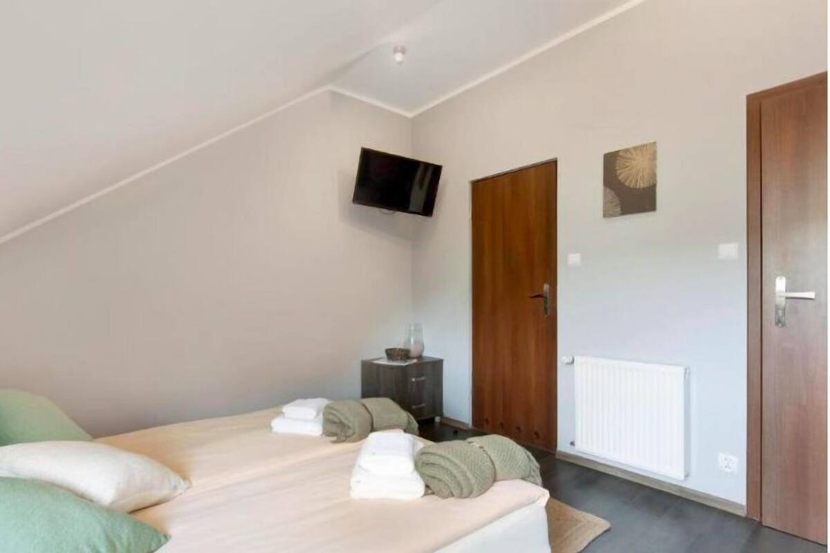 Un dormitorio con cama, televisor montado en la pared y puerta de madera.