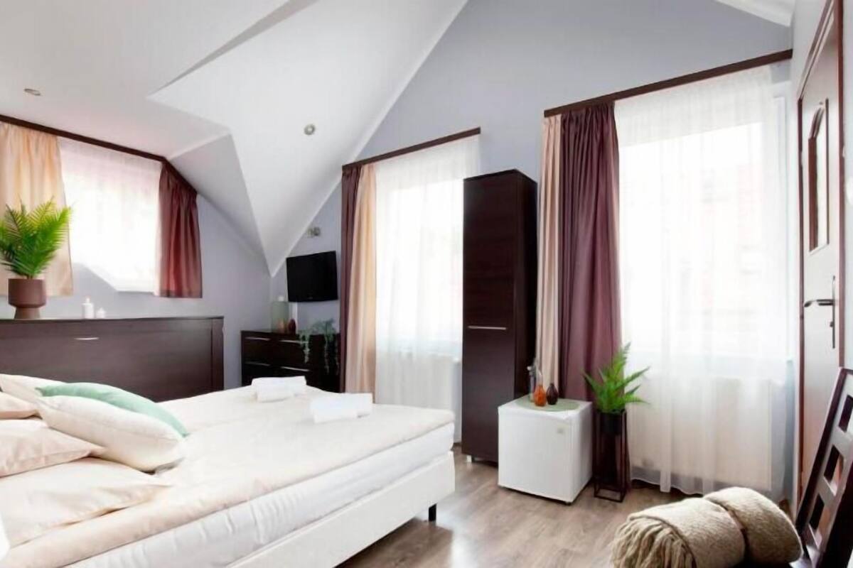 Un dormitorio moderno con una cama, un aparador, un televisor y un armario.