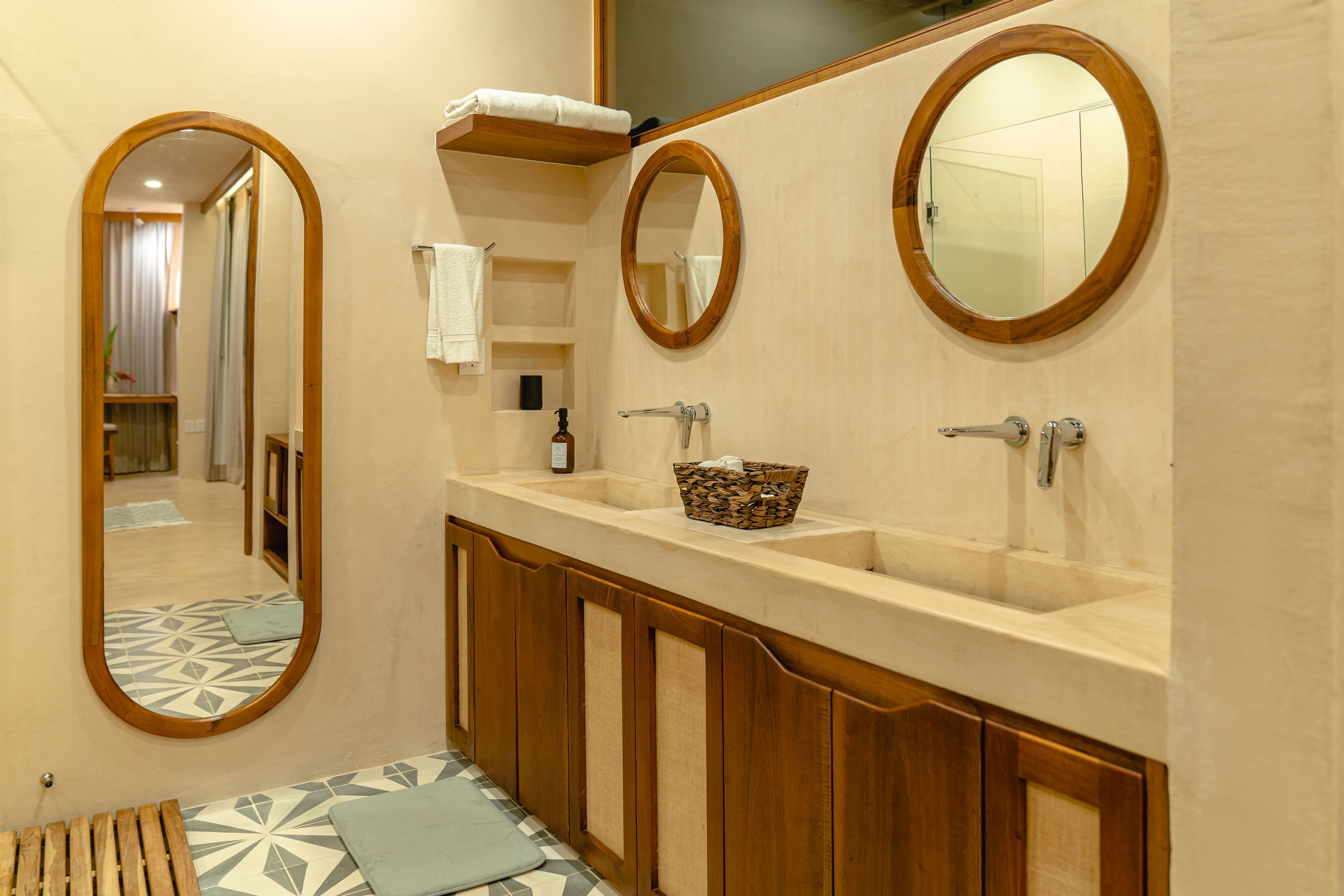 A bathroom with two sinks, wooden cabinets, a mirror, and a patterned floor.