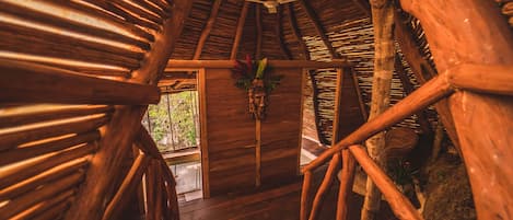 A wooden interior with a thatched roof, wooden beams, and a central door with a decorative hanging.