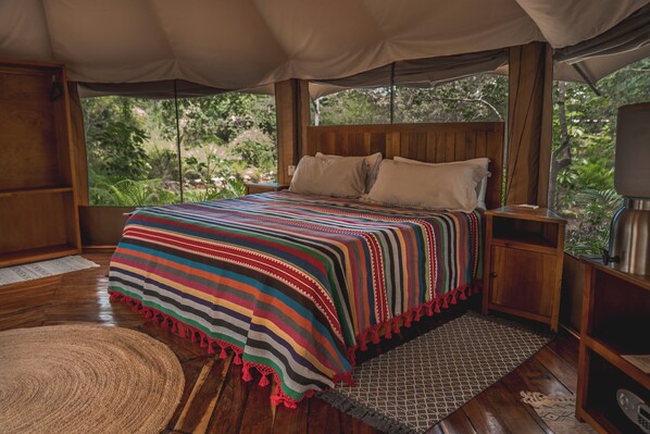 A spacious tent with a wooden bed, a nightstand, and a view of greenery outside. - Destino Mío Mayan Jungle Retreat (Tekit)