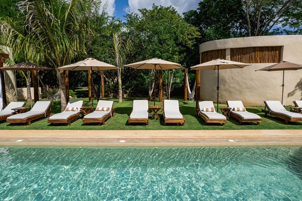 Una piscina al aire libre, sombrillas, sillones reclinables de piscina