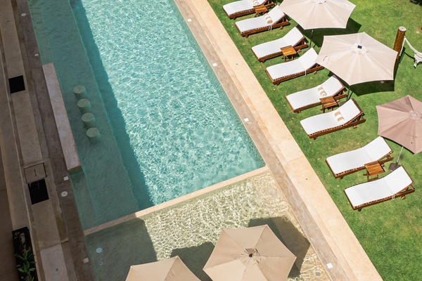 Una piscina al aire libre, sombrillas, sillones reclinables de piscina