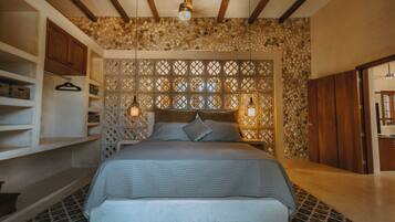 Un dormitorio con cama, cabecera de madera, estanterías y luces colgantes.