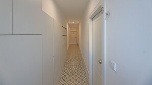 A narrow hallway with patterned flooring, white walls, and a door at the end. - FLH Porto Santa Catarina Cosy Flat (Oporto)