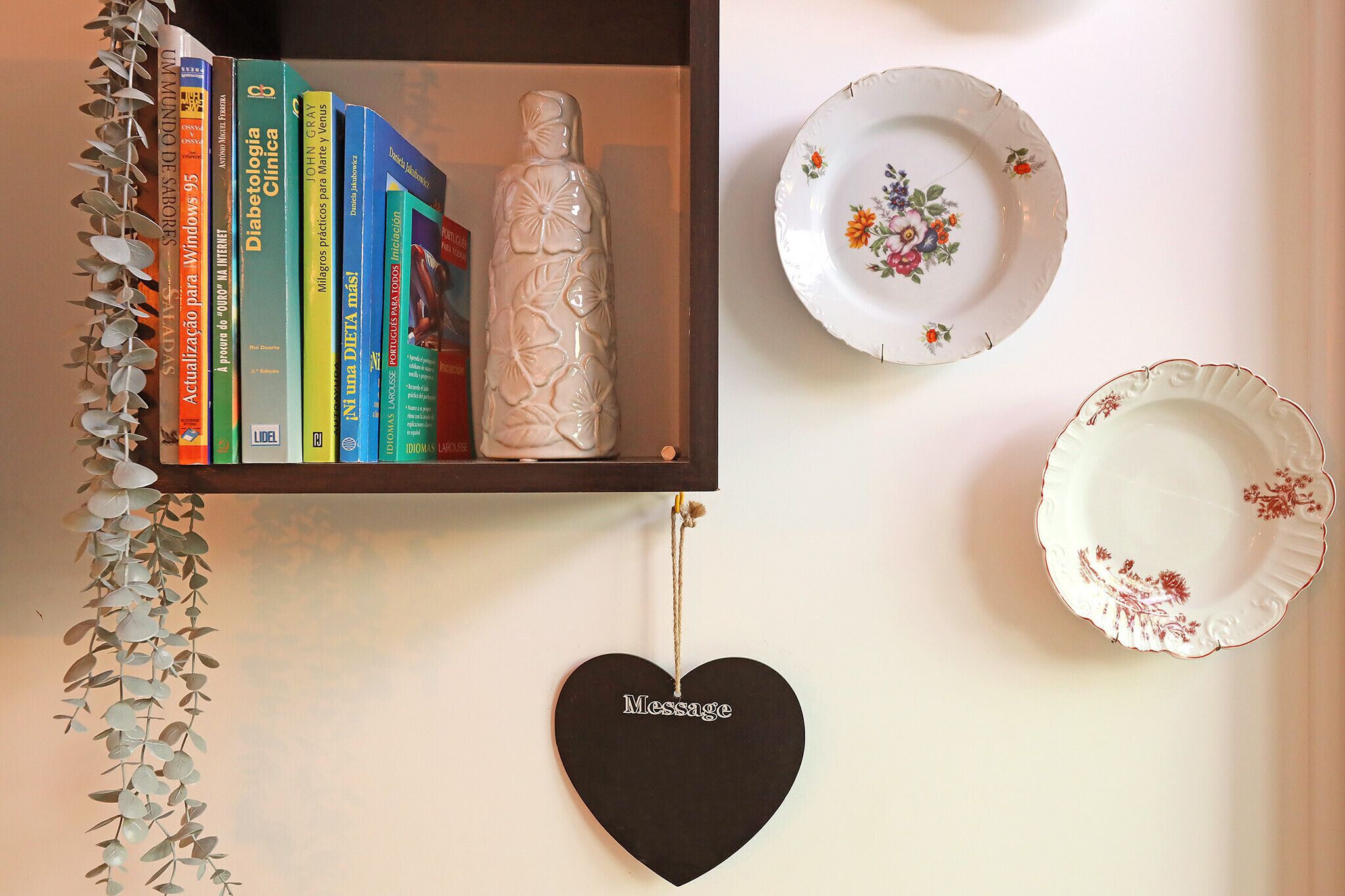 Une bibliothèque remplie de livres, un vase décoratif et un panneau en forme de cœur sur lequel est écrit le mot « Message ».