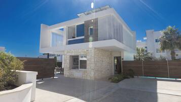 A modern two-story house with a stone facade, a balcony, and a clear sky.