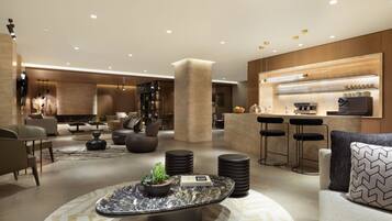 A modern hotel lobby with a bar area, seating arrangements, and a fireplace.