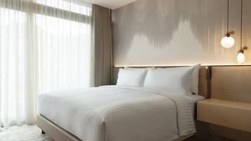 A modern hotel room with a large bed, a nightstand, and a wall-mounted light fixture.